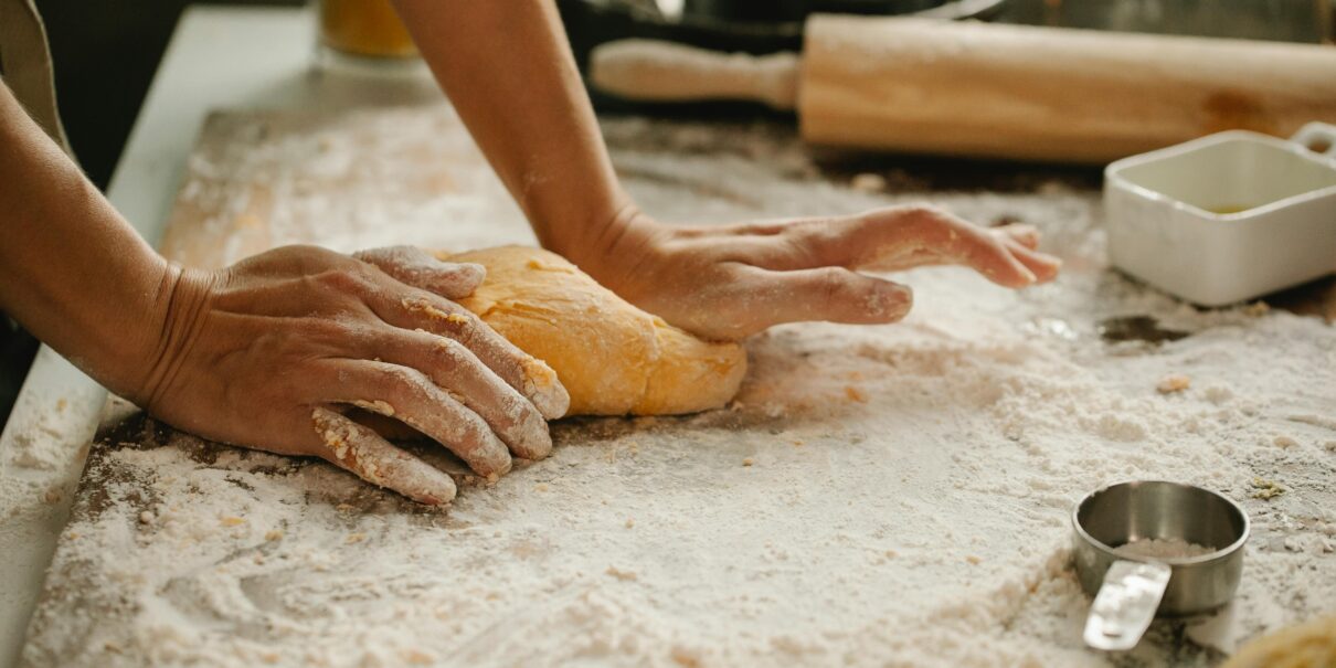 A person kneads fresh dough in a kitchen, showcasing the baking process.