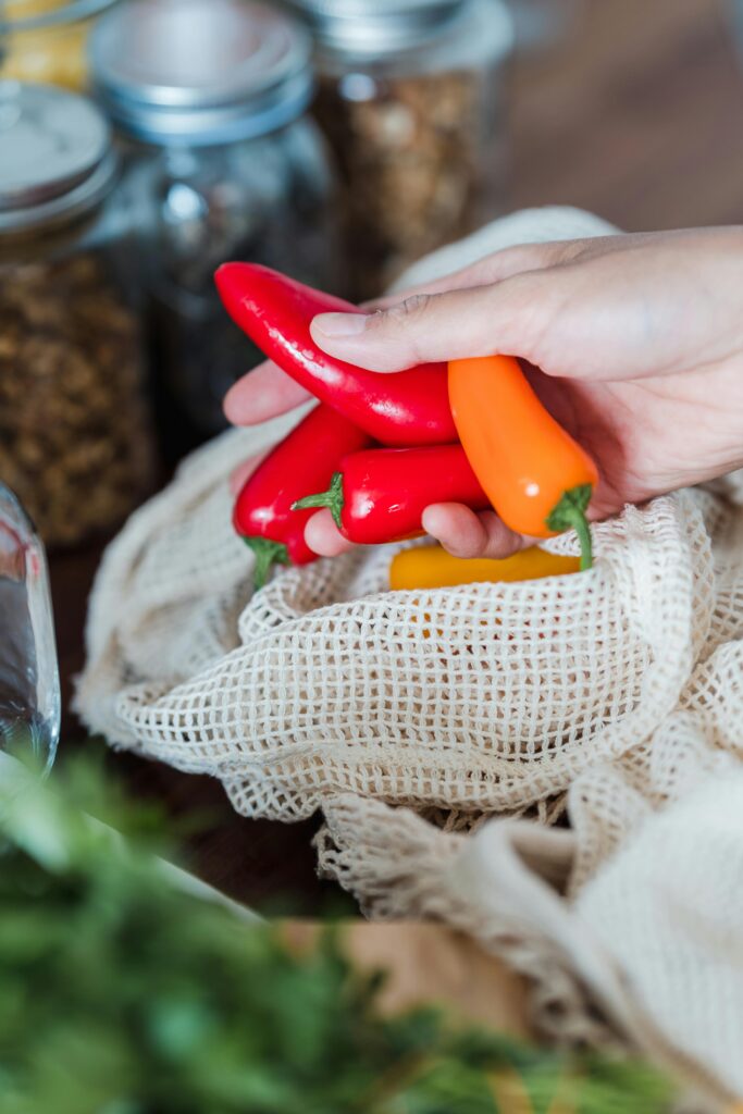 Hand holding colorful red and orange bell peppers in a kitchen setting.